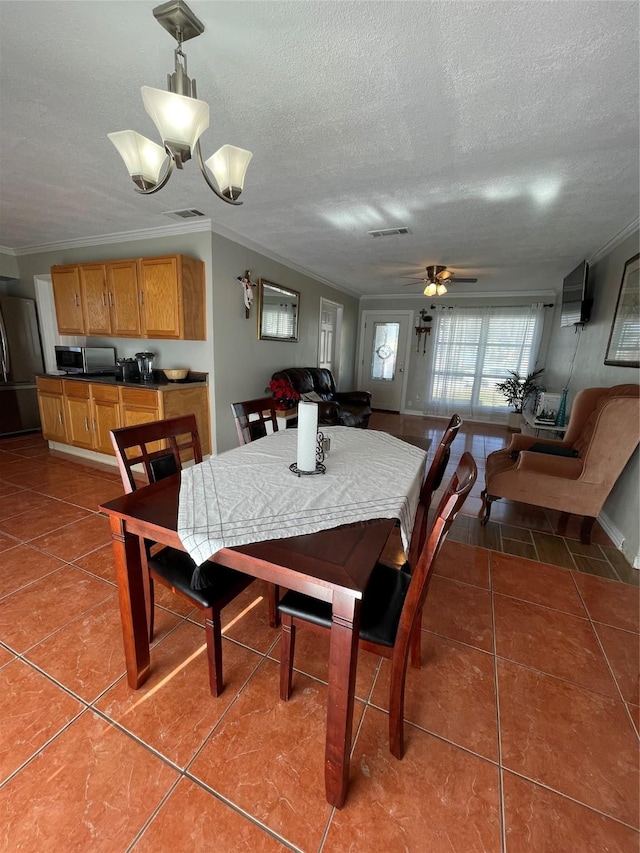 tiled dining room featuring ceiling fan with notable chandelier, ornamental molding, and a textured ceiling