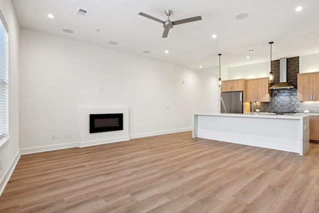 unfurnished living room with ceiling fan, light wood-type flooring, a fireplace, and sink