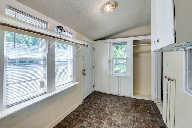 doorway with a textured ceiling and lofted ceiling