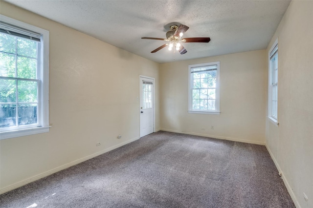 carpeted spare room with a textured ceiling, ceiling fan, and plenty of natural light