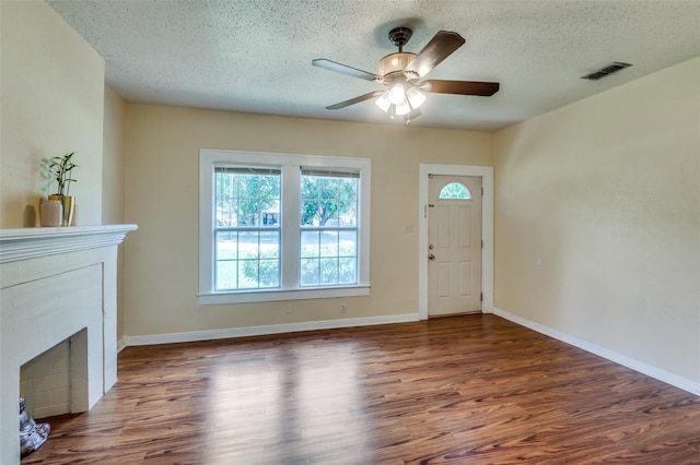 unfurnished living room with ceiling fan, dark wood-type flooring, and a textured ceiling