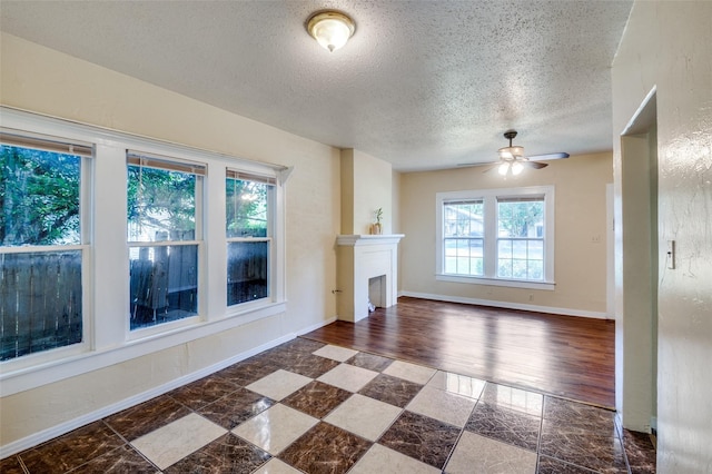 unfurnished living room with ceiling fan and a textured ceiling