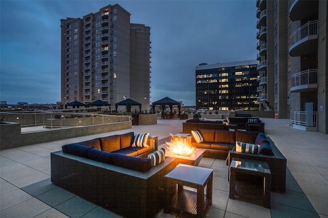 patio terrace at dusk featuring a gazebo and an outdoor living space with a fire pit