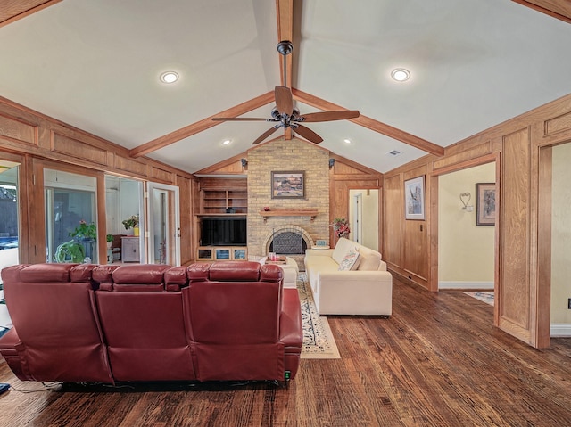 living room featuring wooden walls, ceiling fan, a large fireplace, built in shelves, and lofted ceiling with beams