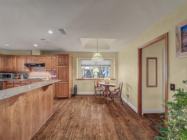 kitchen featuring dark wood-type flooring, stainless steel appliances, decorative backsplash, and hanging light fixtures