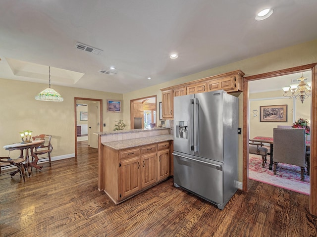 kitchen with kitchen peninsula, decorative light fixtures, high quality fridge, dark wood-type flooring, and light stone countertops