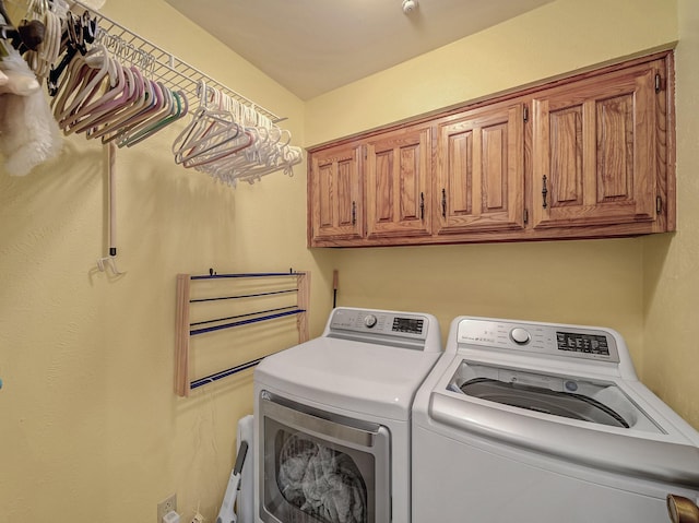 clothes washing area featuring cabinets and washer and clothes dryer