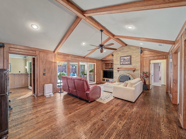 living room with dark wood-type flooring, ceiling fan, a fireplace, and lofted ceiling with beams