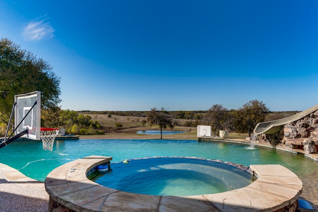 view of swimming pool featuring pool water feature and an in ground hot tub