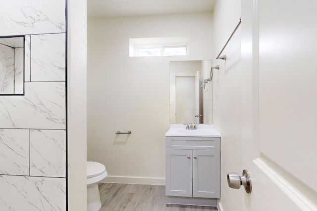 bathroom featuring toilet, vanity, a shower, and hardwood / wood-style flooring