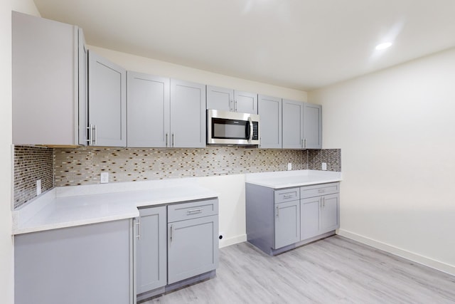 kitchen with tasteful backsplash, gray cabinets, and light hardwood / wood-style flooring