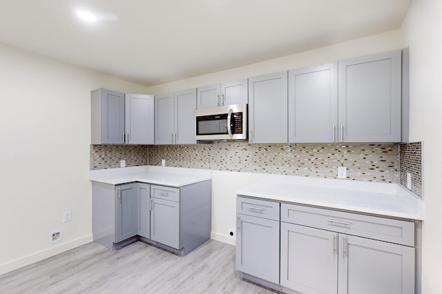 kitchen featuring gray cabinets, backsplash, and light hardwood / wood-style flooring