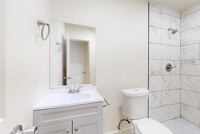 bathroom with toilet, a tile shower, and vanity