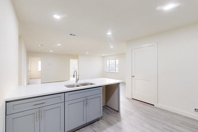 kitchen with light hardwood / wood-style floors, sink, and gray cabinetry