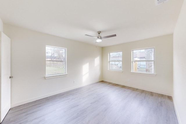 empty room featuring ceiling fan, light wood-type flooring, and plenty of natural light