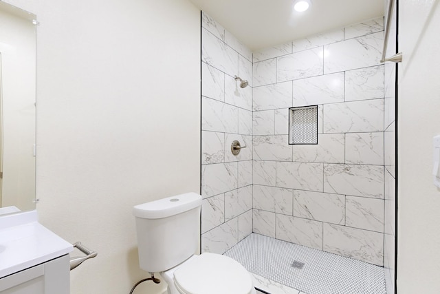 bathroom with toilet, vanity, and tiled shower