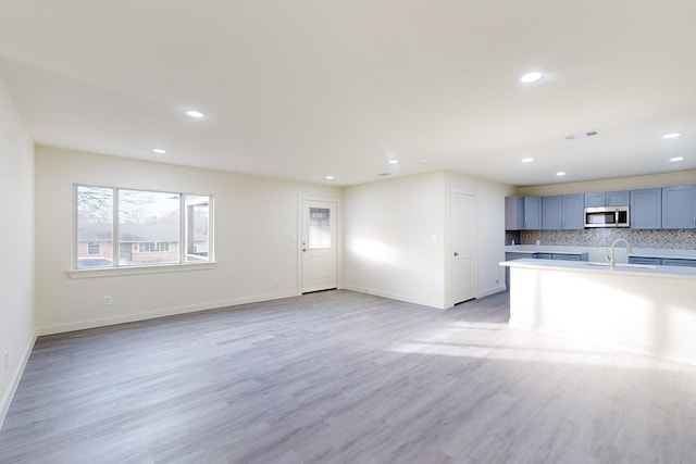 unfurnished living room featuring sink and light hardwood / wood-style flooring