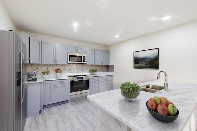 kitchen with appliances with stainless steel finishes, decorative backsplash, kitchen peninsula, and sink