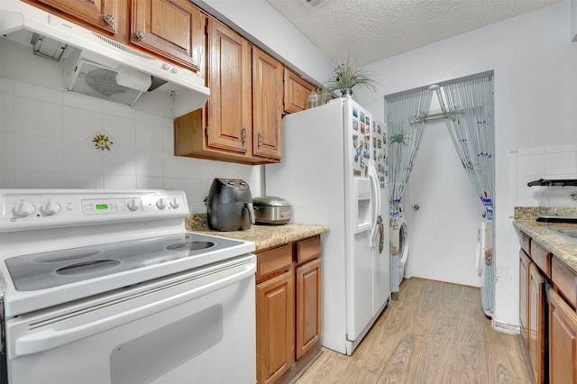 kitchen featuring tasteful backsplash, white appliances, light wood-type flooring, a textured ceiling, and washer / clothes dryer