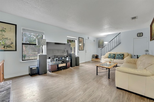 living room with plenty of natural light, a textured ceiling, and light hardwood / wood-style floors