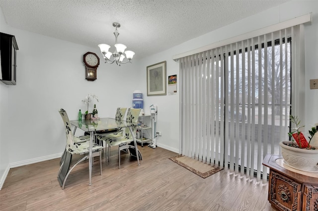 dining area with a textured ceiling, hardwood / wood-style flooring, and a notable chandelier