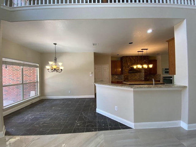 kitchen featuring tasteful backsplash, oven, pendant lighting, kitchen peninsula, and a chandelier