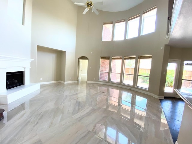 unfurnished living room with ceiling fan and a towering ceiling