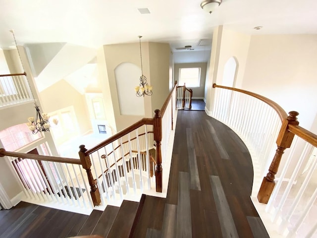 stairs featuring hardwood / wood-style flooring and an inviting chandelier