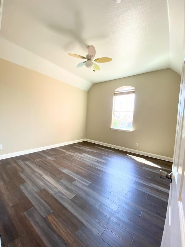 empty room with vaulted ceiling, ceiling fan, dark hardwood / wood-style flooring, and a textured ceiling