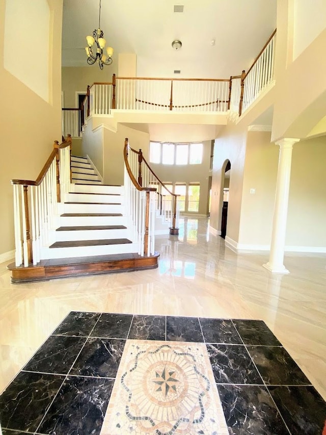 foyer with an inviting chandelier, a towering ceiling, and decorative columns