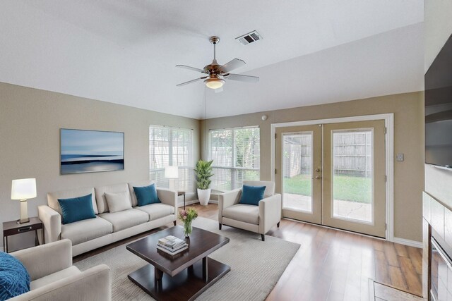 unfurnished living room with a tile fireplace, vaulted ceiling, ceiling fan, and light wood-type flooring