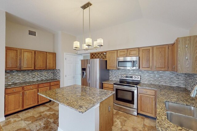 kitchen with light stone counters, a center island, a chandelier, appliances with stainless steel finishes, and pendant lighting