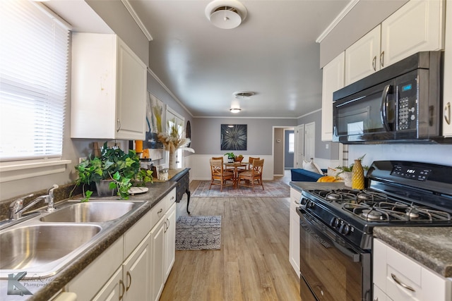 kitchen with light hardwood / wood-style floors, black appliances, sink, ornamental molding, and white cabinets