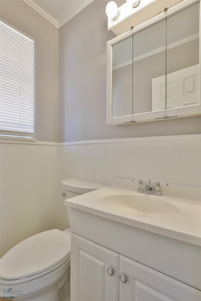 bathroom featuring toilet, vanity, and crown molding