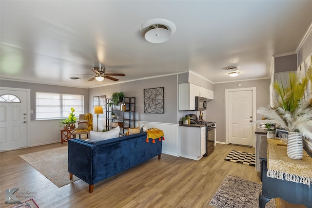 living room with light hardwood / wood-style floors, ornamental molding, and ceiling fan