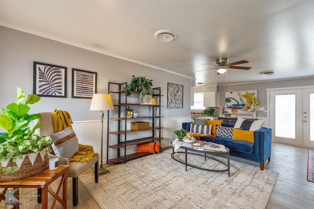 living room featuring ceiling fan, ornamental molding, light hardwood / wood-style flooring, and french doors