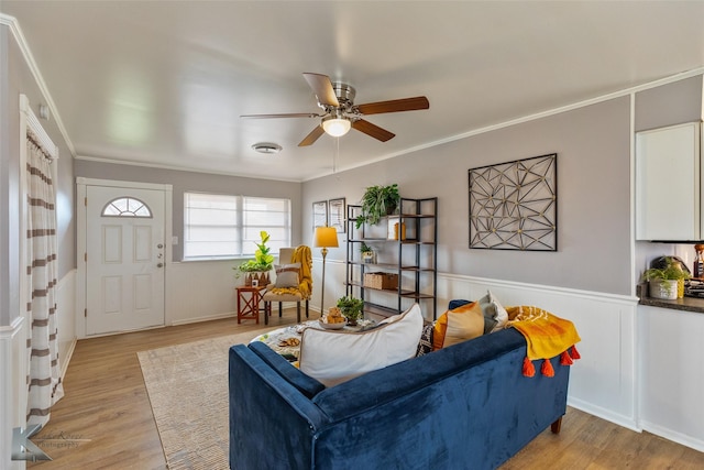 living room featuring light wood-type flooring, ceiling fan, and crown molding