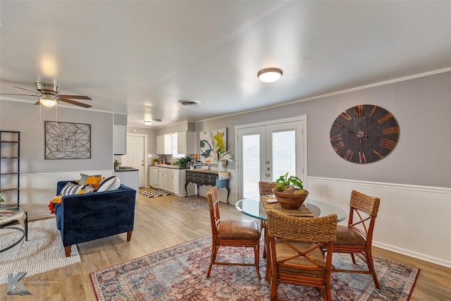 dining space featuring light wood-type flooring, ceiling fan, crown molding, and french doors