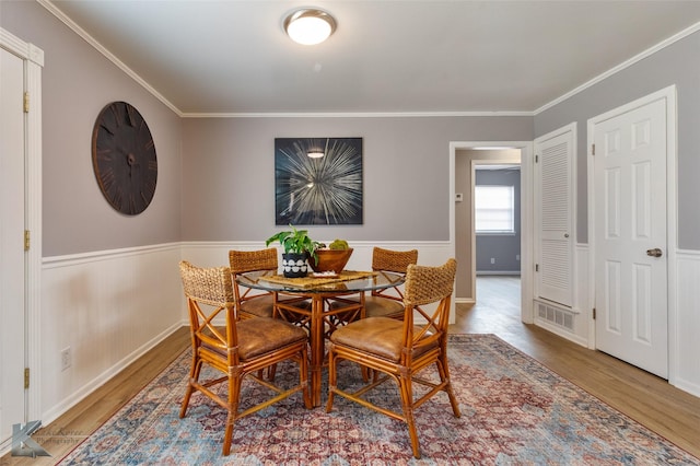 dining area with ornamental molding and hardwood / wood-style flooring