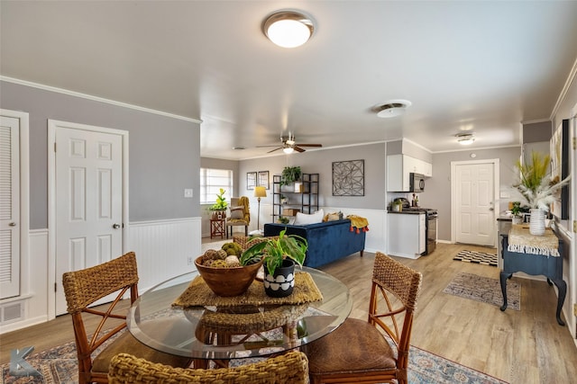 dining area with ceiling fan, ornamental molding, and light hardwood / wood-style flooring