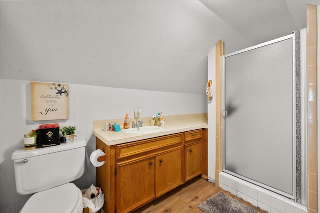 bathroom with toilet, vanity, vaulted ceiling, wood-type flooring, and a shower with door