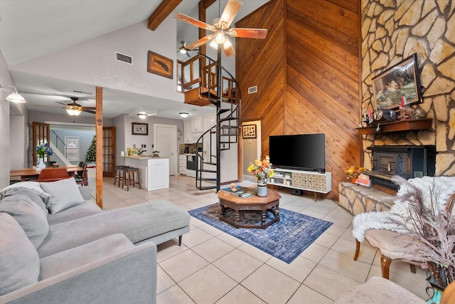 living room with wooden walls, ceiling fan, high vaulted ceiling, light tile patterned floors, and beam ceiling