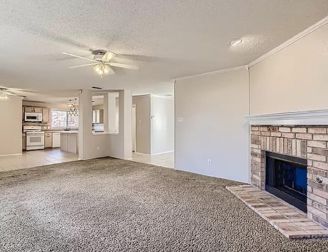 unfurnished living room featuring light carpet, ceiling fan with notable chandelier, crown molding, and a fireplace