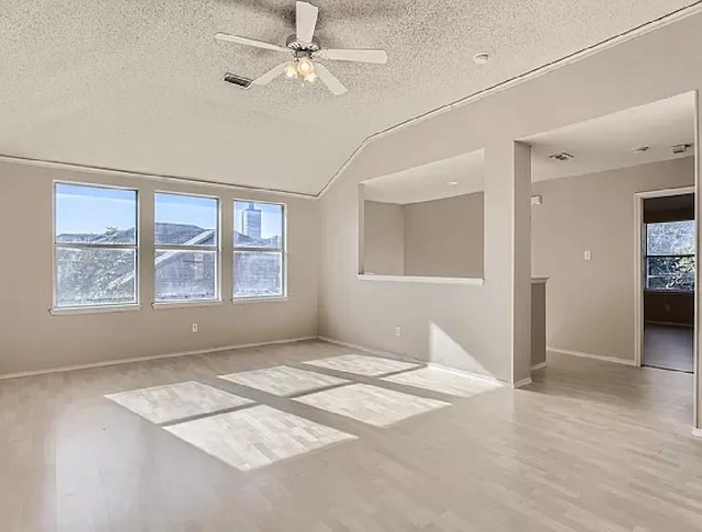 empty room featuring light wood-type flooring, vaulted ceiling, a textured ceiling, and ceiling fan