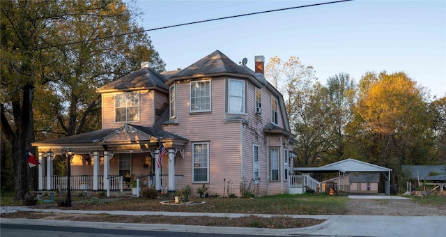 victorian-style house featuring a porch and a carport