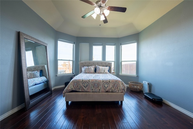 bedroom with ceiling fan, dark wood-type flooring, and a tray ceiling