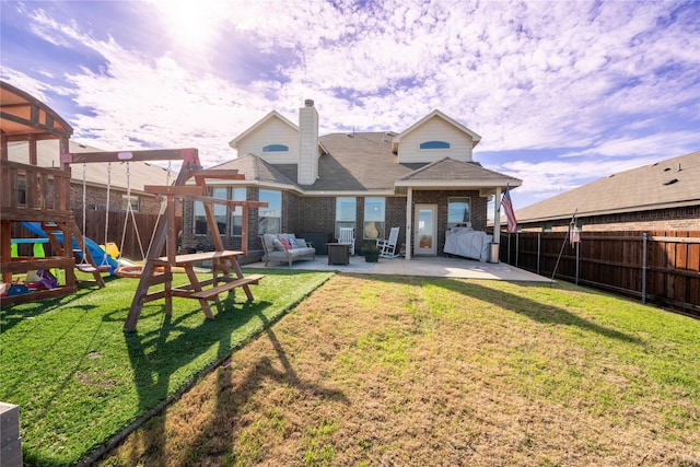 back house at dusk with a lawn, an outdoor hangout area, a patio area, and a playground