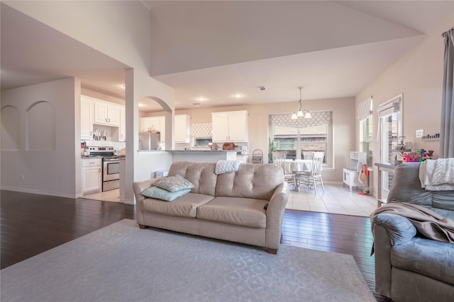 living room with light wood-type flooring, a notable chandelier, and vaulted ceiling