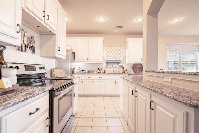 kitchen with white cabinets, light tile patterned floors, light stone counters, and stainless steel appliances