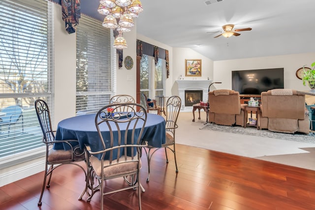 dining area featuring ceiling fan, lofted ceiling, and wood-type flooring